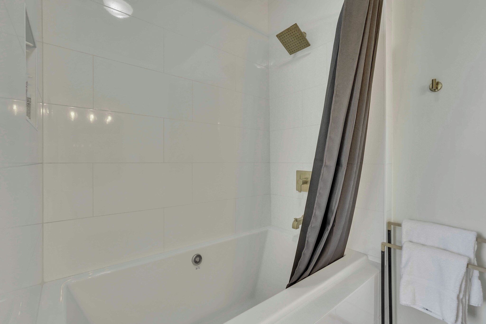 A modern bathroom with a bathtub, a shower area, and a towel rack with towels.