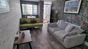 A living room with a green sofa, a grey sofa, a small table with a plant, and a window with bars. - The Hideaway ll /private garden/Quiet/Central (Southport)