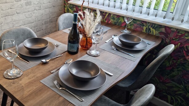A wooden dining table set with black bowls, wine glasses, and cutlery. - The Hideaway ll /private garden/Quiet/Central (Southport)