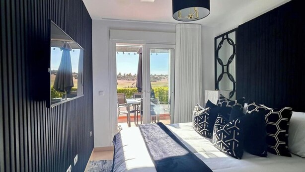 Un dormitorio moderno con una cama grande, un televisor y vistas al exterior.