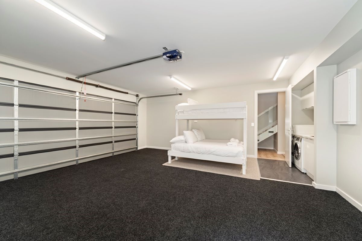 Een slaapkamer met een stapelbed, een wasmachine en een opslagruimte.