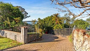 A paved pathway leading to a gated entrance surrounded by lush greenery and trees.