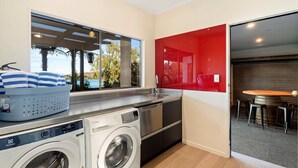 A compact kitchen with a washing machine, a sink, and a red accent wall.