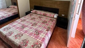 A bedroom with two beds, a wooden headboard, an air conditioning unit, and a mirror.