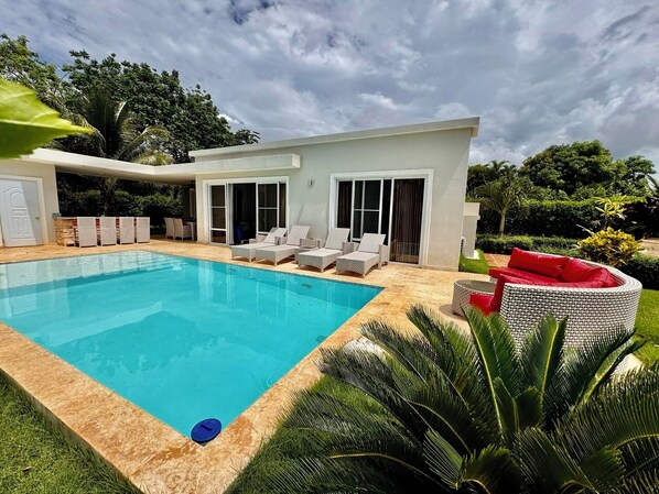 Uma casa moderna com piscina, área de estar externa e vegetação exuberante.