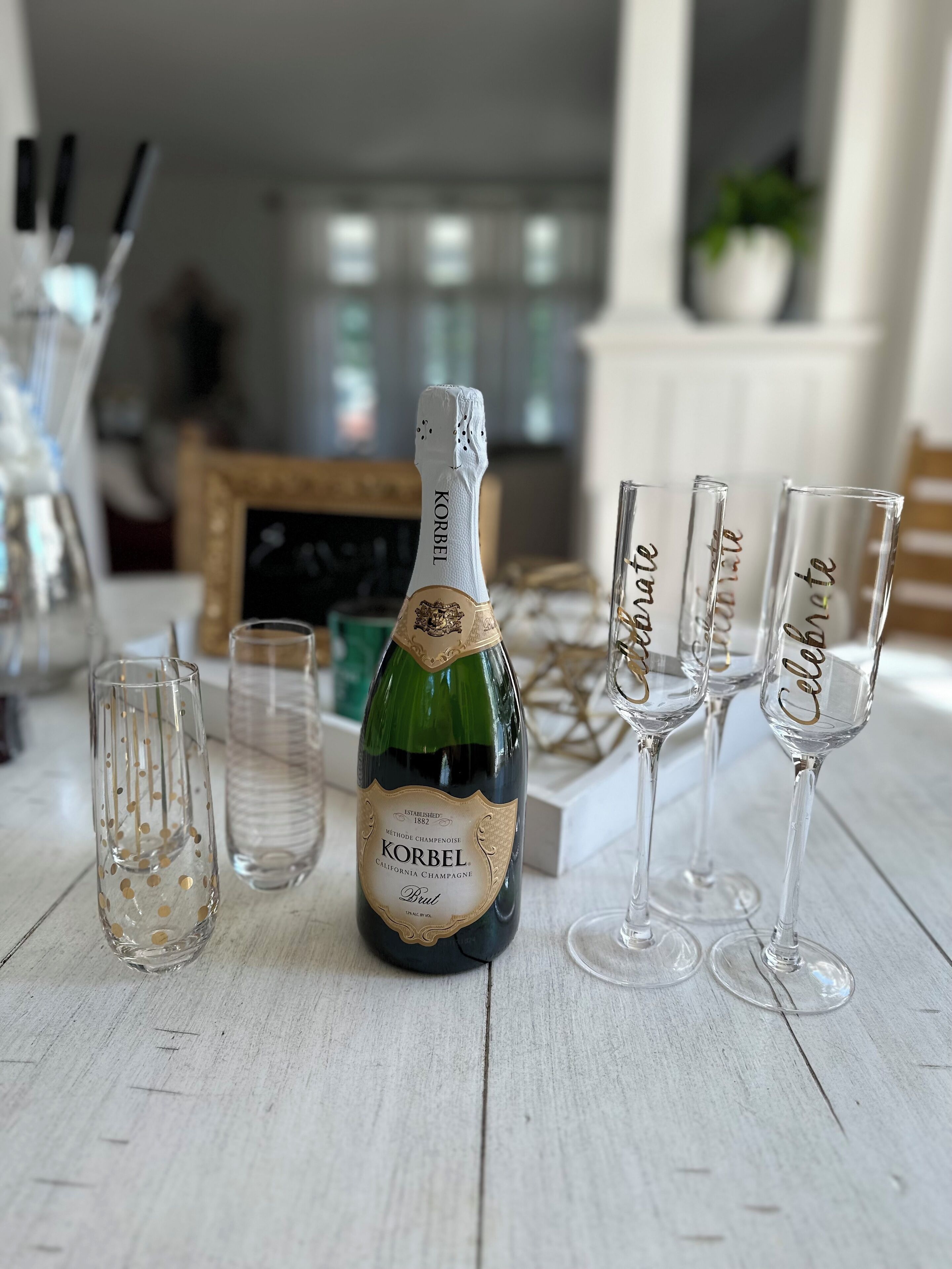 Een fles Korbel champagne en drie glazen op een houten tafel.