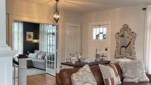 A spacious living room with a brown leather sofa, a wooden coffee table, and a chandelier. - Charming Pet-Friendly Stay: Walk BC, 7.5 mi to JMU, walk to Dining, Parks & more (Bridgewater)