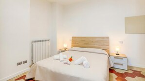 Ein Hotelzimmer mit einem Bett, zwei Nachttischen mit Lampen, einem Heizkörper und einem Fußboden mit geometrischem Muster.
