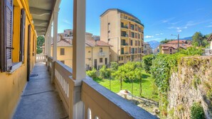 Ein Balkon mit Blick auf ein Wohngebiet, darunter Gebäude und ein Berg im Hintergrund.
