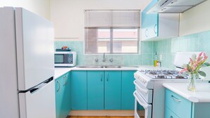 A kitchen with teal cabinets, a white refrigerator, a microwave, a sink, and a stove. - Spacious & Cosy self-contained 1 bedroom apartment
 (Rivervale)