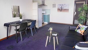 A compact living space with a dining area, a sofa, a small coffee table, and a kitchen in the background. - Spacious & Cosy self-contained 1 bedroom apartment
 (Rivervale)