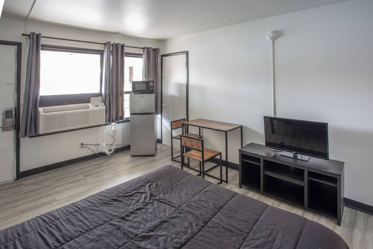 Une chambre d’hôtel équipée d’un lit, d’un bureau, d’une chaise, d’une télévision et d’un appareil de climatisation.