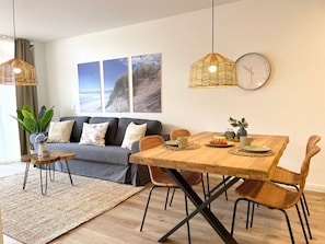 Un salon moderne avec un canapé, une table à manger, des chaises et des œuvres d’art accrochées au mur.
