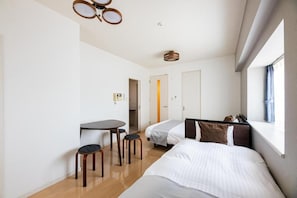 Une chambre d’hôtel avec un lit, un bureau, deux chaises, une fenêtre et une porte.