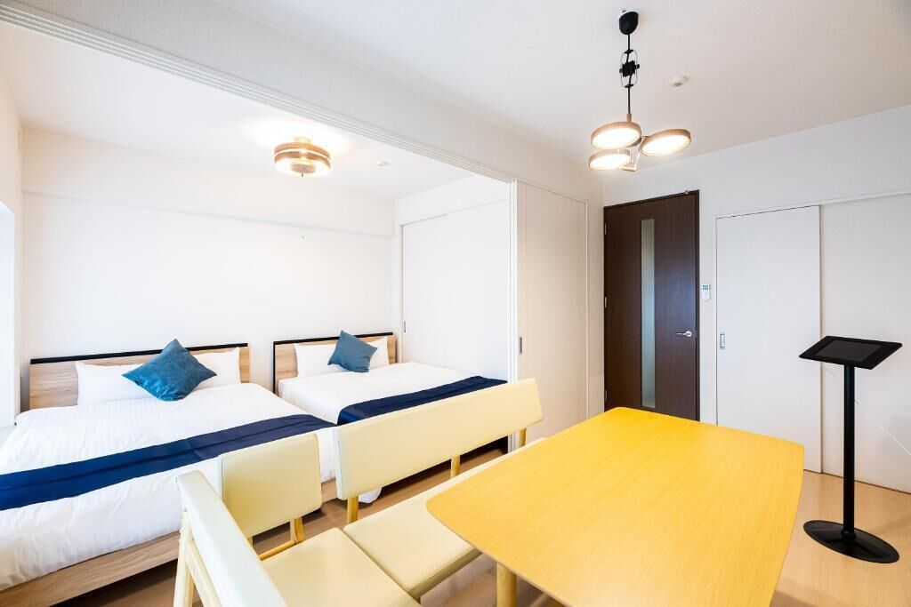 A hotel room with two beds, a small table, and a desk with a computer.