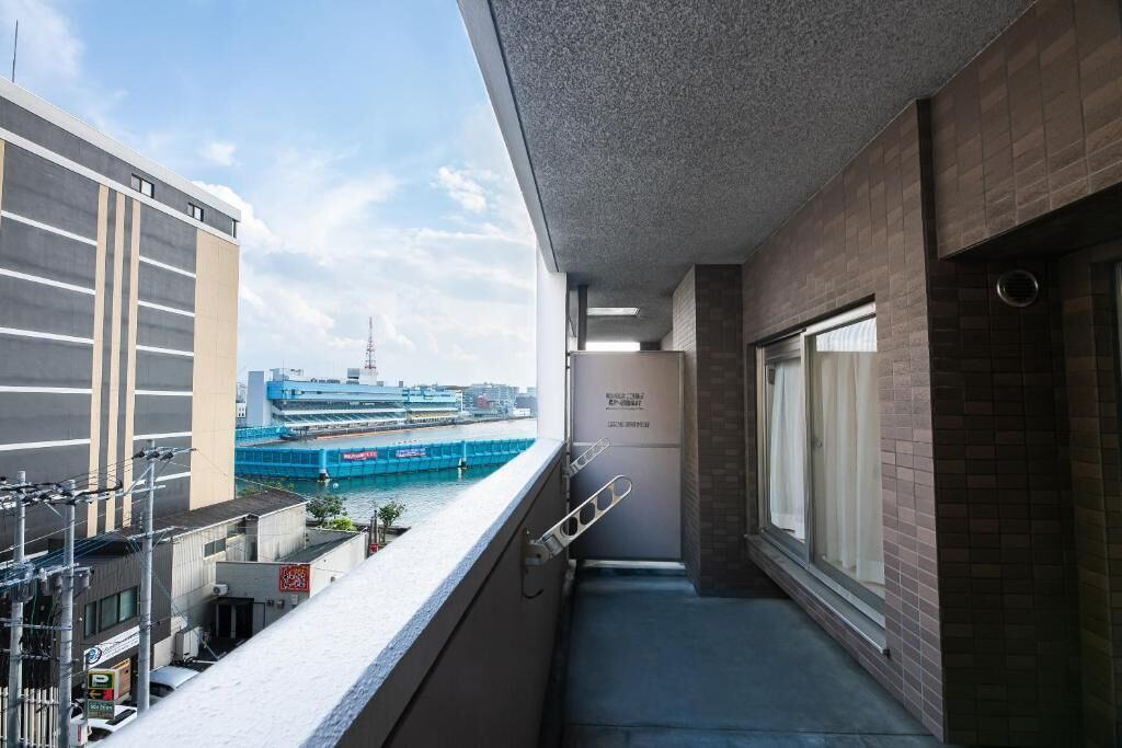 A balcony with a view of a cruise ship and a building across the water.