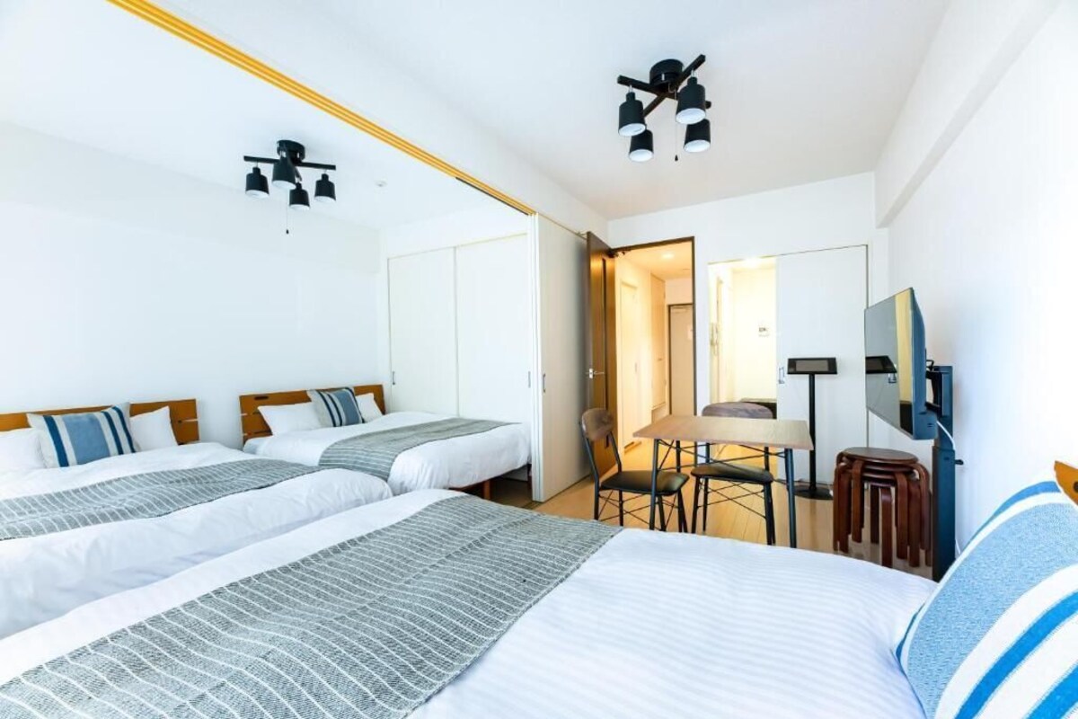 Una habitación de hotel con dos camas, un escritorio, una silla, un televisor y un espejo.