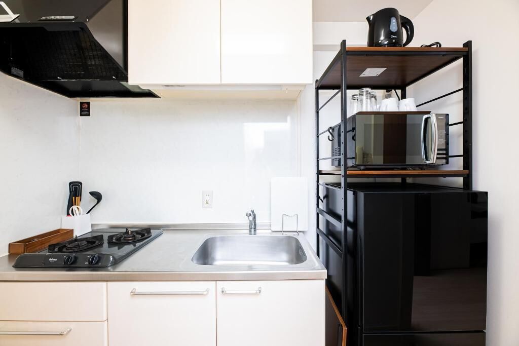 A modern kitchen with a gas stove, sink, and black shelving unit holding kitchen appliances.