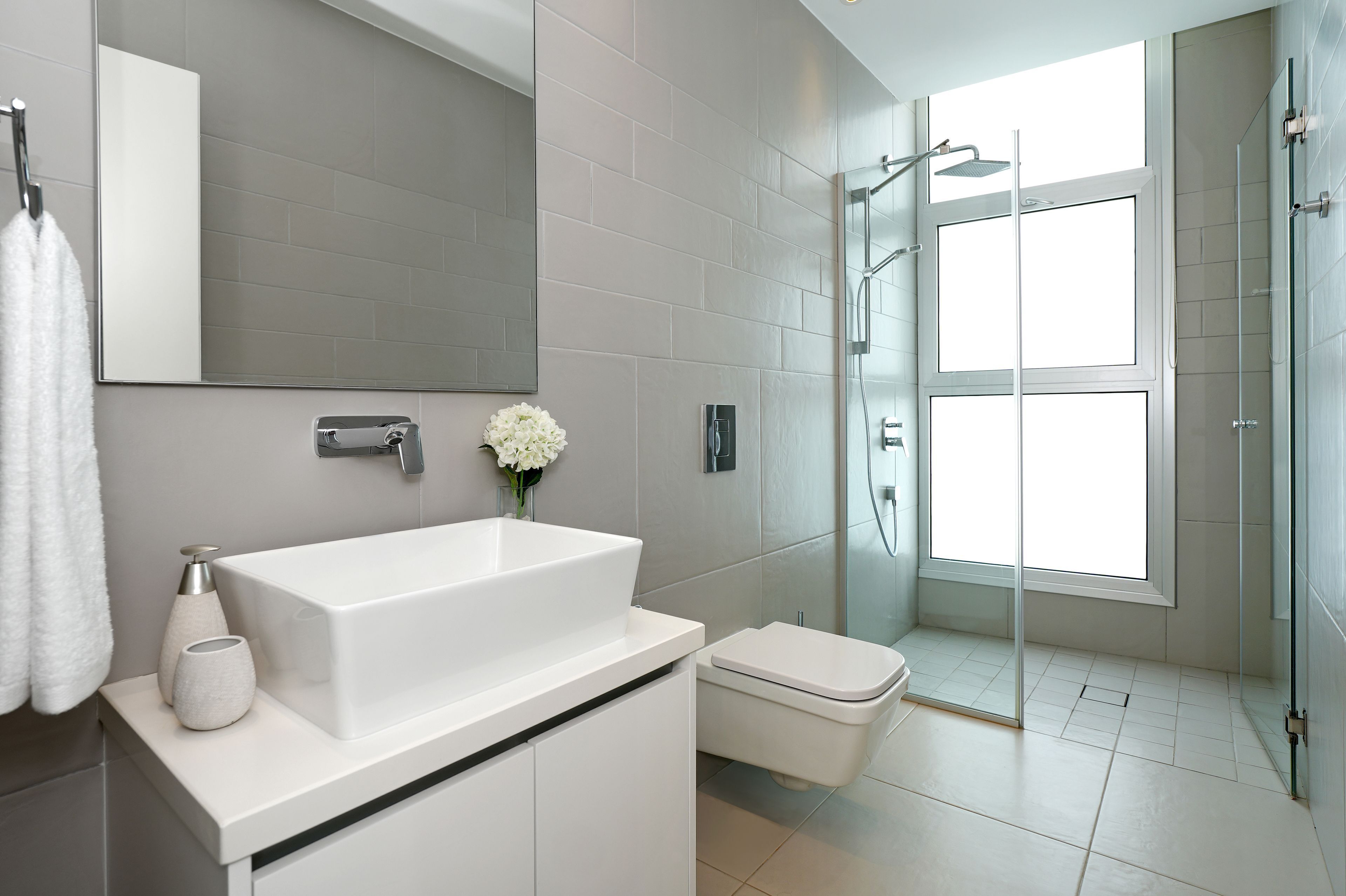Un bany modern amb un lavabo gran de color blanc, un vàter i una zona de dutxa amb envàs de vidre.