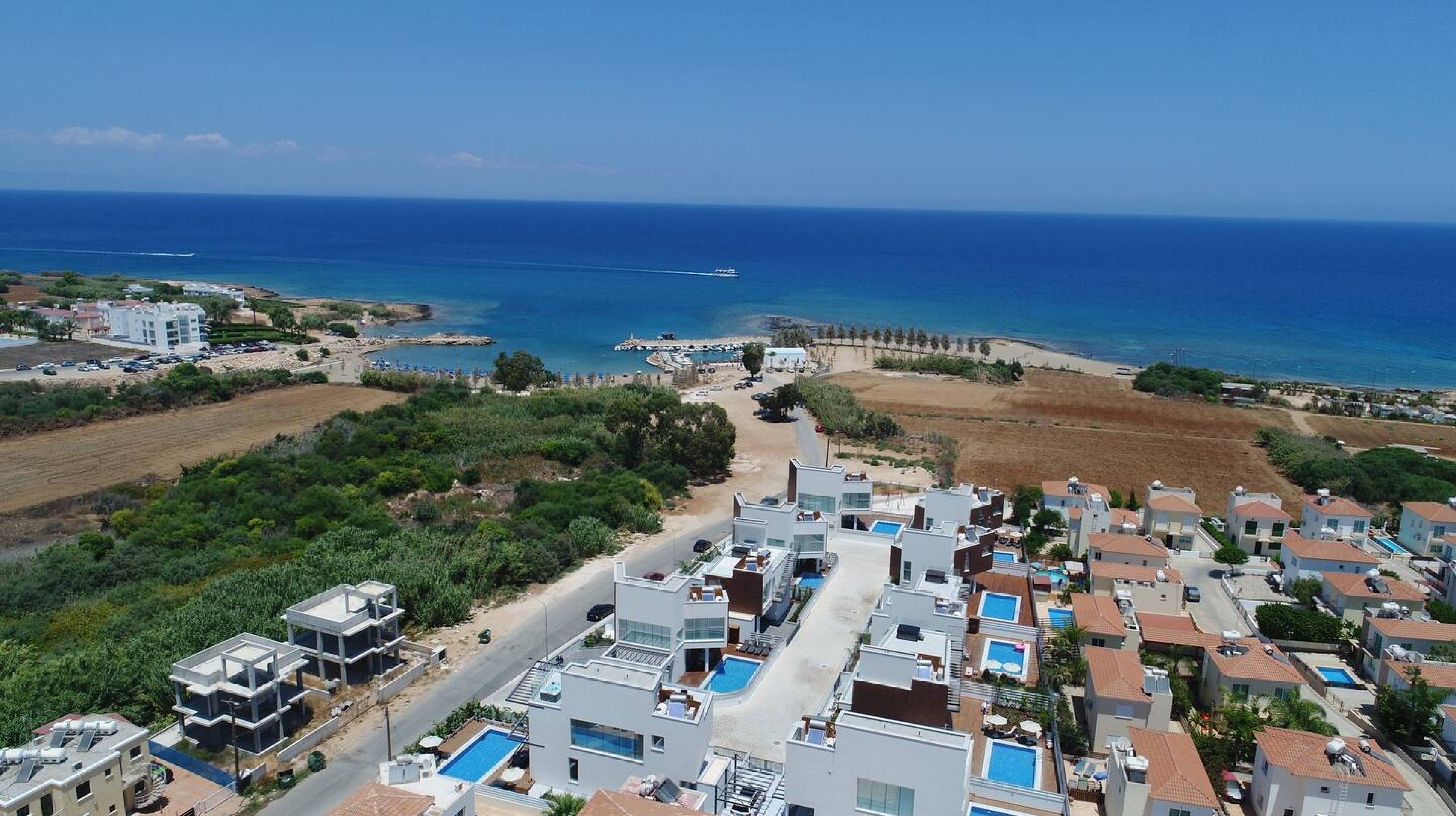 Un quartier résidentiel situé sur la côte, avec des maisons modernes, une piscine et une vue sur la mer.