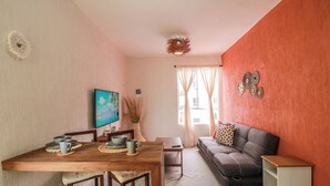 Una sala de estar con una mesa de comedor de madera, un sofá y un televisor.