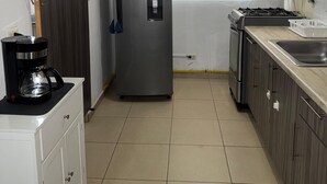 A compact kitchen with a refrigerator, stove, and sink. - Apartamento a Solo 15 Minutos del Aeropuerto con Piscina (Panamá)