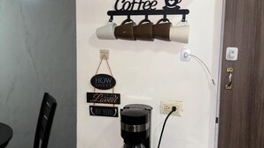 A coffee station with a coffee maker, cups, and decorative signs on the wall. - Apartamento a Solo 15 Minutos del Aeropuerto con Piscina (Panamá)