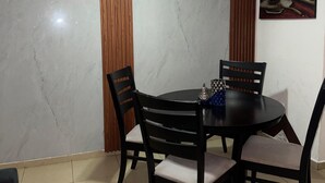 A dining area with a round table, four chairs, a ceiling fan, and a wall-mounted light. - Apartamento a Solo 15 Minutos del Aeropuerto con Piscina (Panamá)