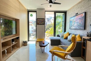 A modern living room with a flat-screen TV, a sofa, a yellow armchair, and a coffee table.
