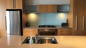 Une cuisine moderne dotée d’appareils électroménagers en acier inoxydable, de meubles en bois et d’un îlot central avec un évier.