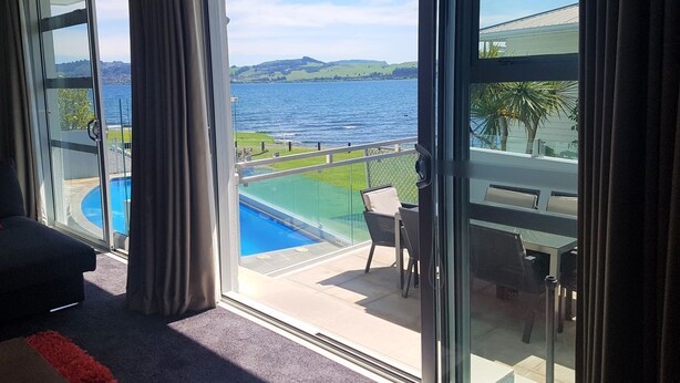 Un balcon avec piscine, un coin repas et une vue sur la mer et les collines.