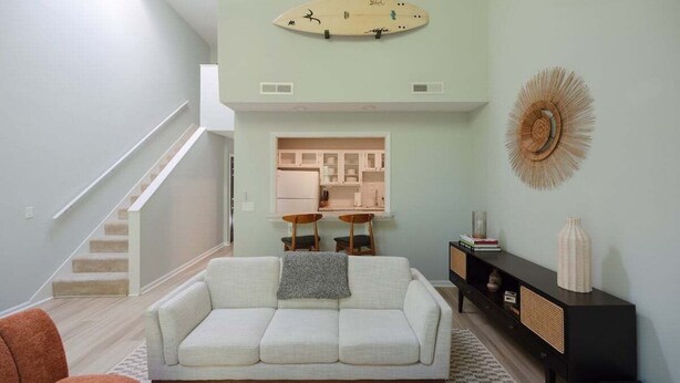 Una sala de estar con un sofá blanco, una consola negra y una decoración con una tabla de surf en la pared.