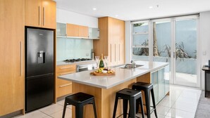 Una cocina moderna con una isla grande, electrodomésticos de acero inoxidable y un ventanal corredero al exterior.