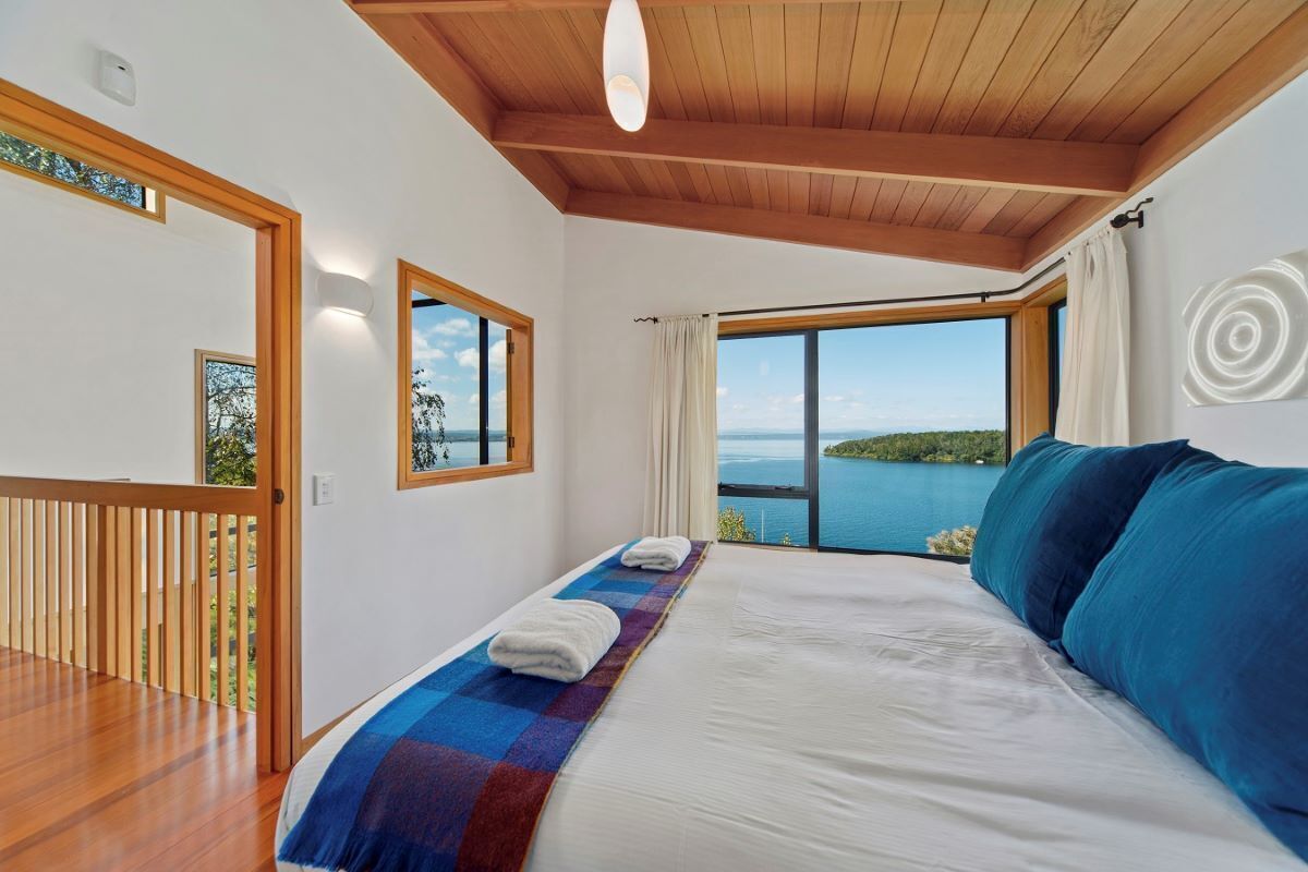 Ein Schlafzimmer mit einem großen Bett, Meerblick und Holzbalken an der Decke.