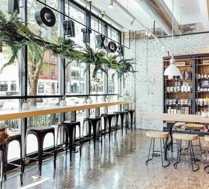 A modern cafe with large windows, black bar stools, and indoor plants. - LUX 3-Level Chicago Home +garage & patio (Chicago)