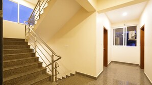 Una escalera de granito con barandillas de metal, que conduce a un rellano con una puerta y un ventanal.