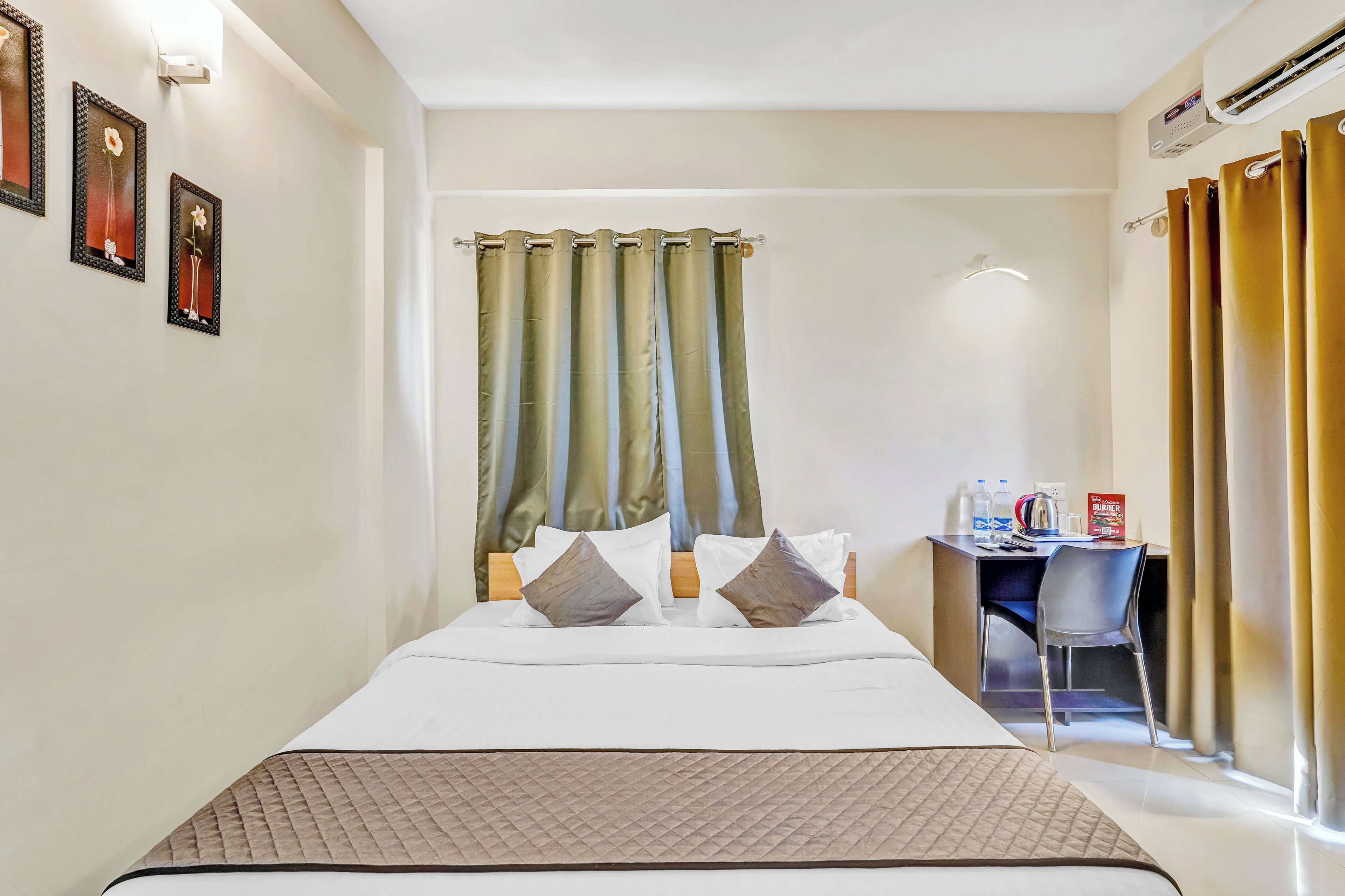 Habitación de hotel con cama, escritorio y silla. En la pared, tres cuadros enmarcados.