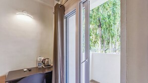 Una habitación con escritorio, silla y ventana con vista a zonas verdes.