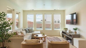 A spacious living room with a sectional sofa, a round coffee table, and a TV mounted on the wall. - Red Rock Haven - NEW Private Pool, putting green, & more. Perfect family retreat (Washington)
