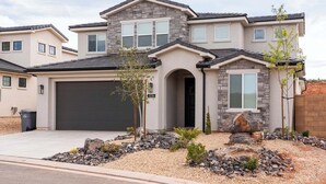 A modern two-story house with a stone facade, a garage, and a landscaped front yard with rocks and small plants. - Red Rock Haven - NEW Private Pool, putting green, & more. Perfect family retreat (Washington)