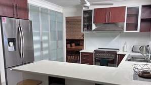 A modern kitchen with a stainless steel refrigerator, a built-in oven, and a large island with bar stools.