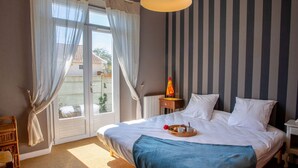 Hotellihuone, jossa on suuri sänky, yöpöytä, tuoli ja näkymä ikkunasta.