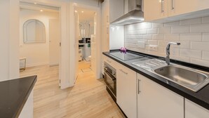 Una cucina moderna con mobili bianchi, un piano di lavoro nero e elettrodomestici in acciaio inossidabile.