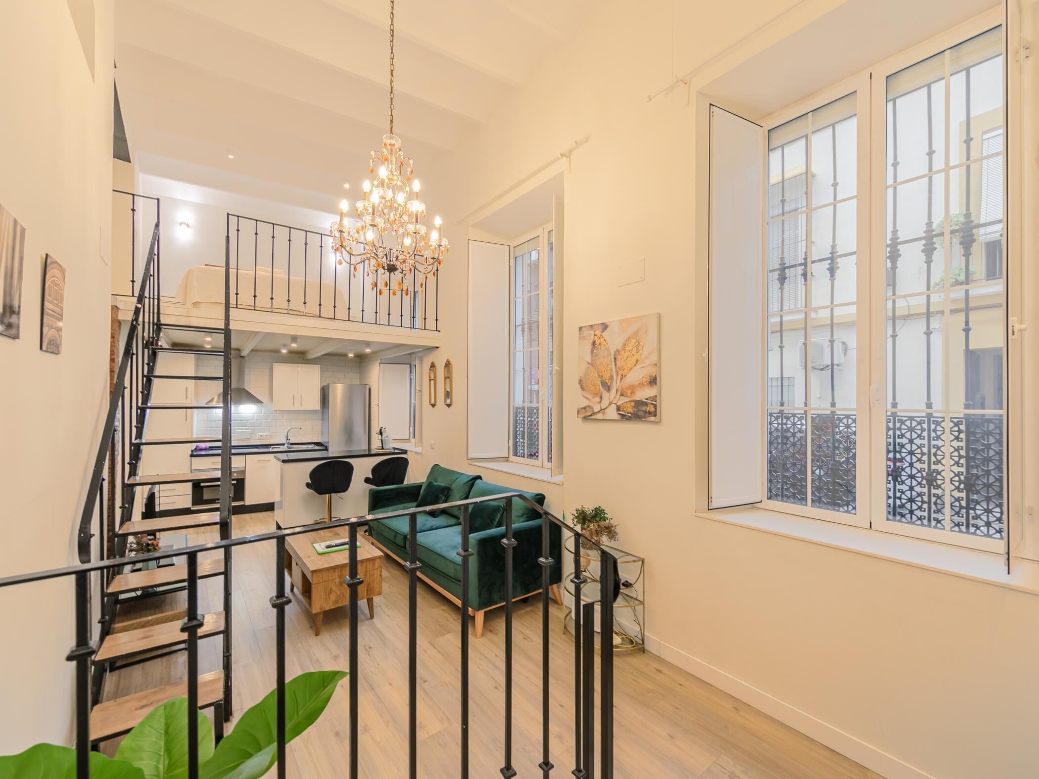 Eine moderne Wohnung mit Treppe, Essbereich, grünem Sofa und großen Fenstern.