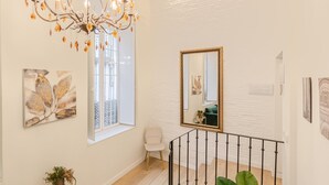Una stanza spaziosa con un lampadario, una grande finestra, uno specchio e opere d'arte alle pareti.