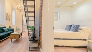 Un interno moderno con una scala, un divano verde, un tavolino in legno e un letto con cuscini blu.