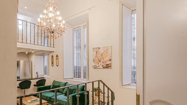 Un soggiorno moderno con un divano verde, un tavolino in legno e un lampadario.
