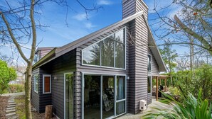 Una casa moderna de dos pisos con amplios ventanales correderos y un patio cubierto.