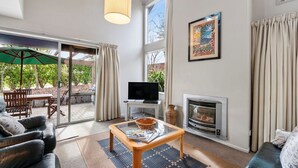 Una sala de estar con chimenea, televisor y mesa de centro de vidrio.