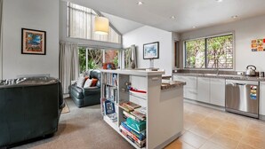 Una cocina moderna con armarios blancos, lavavajillas integrado y un ventanal grande.